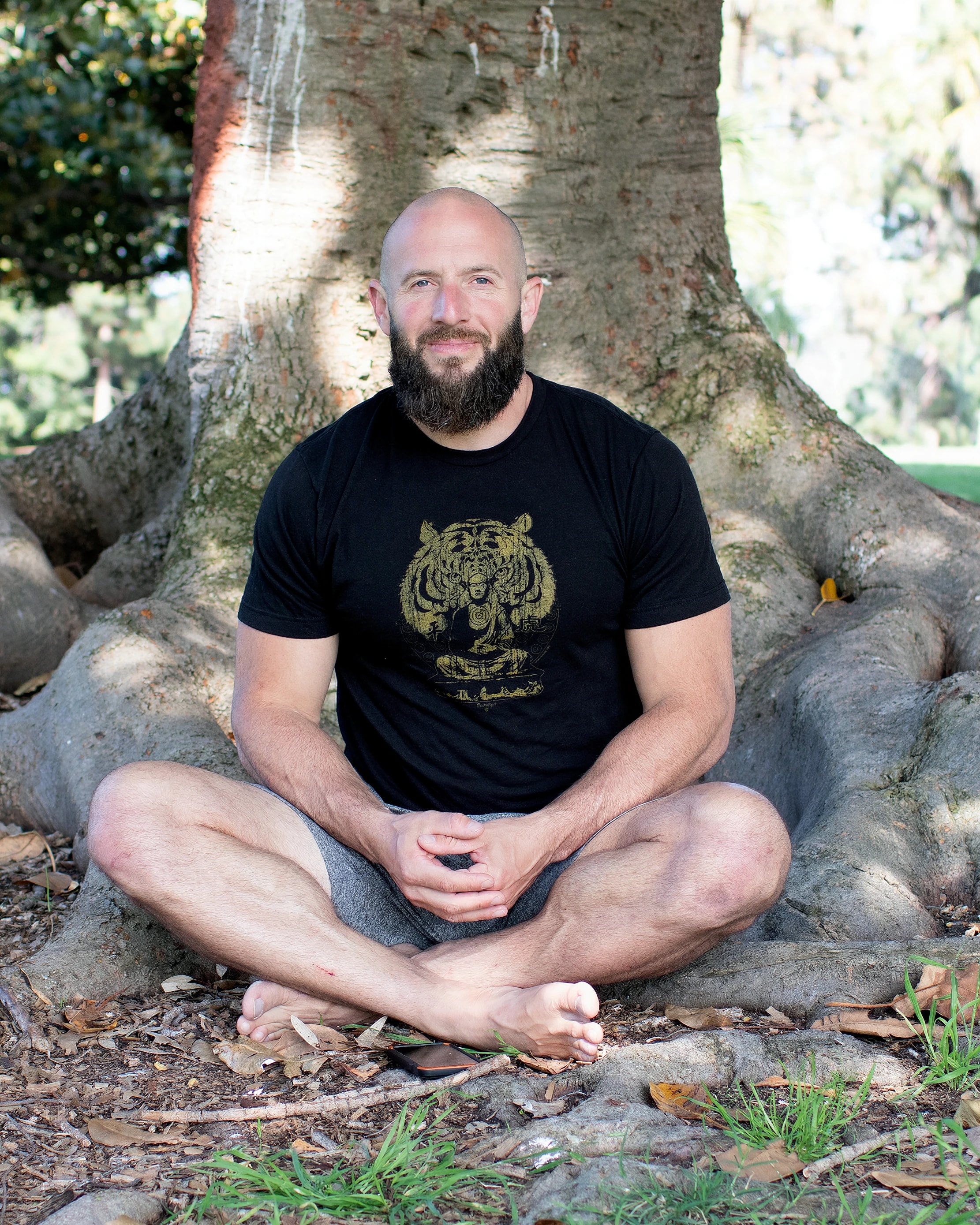 Miles sitting cross-legged among the roots of a banyan tree