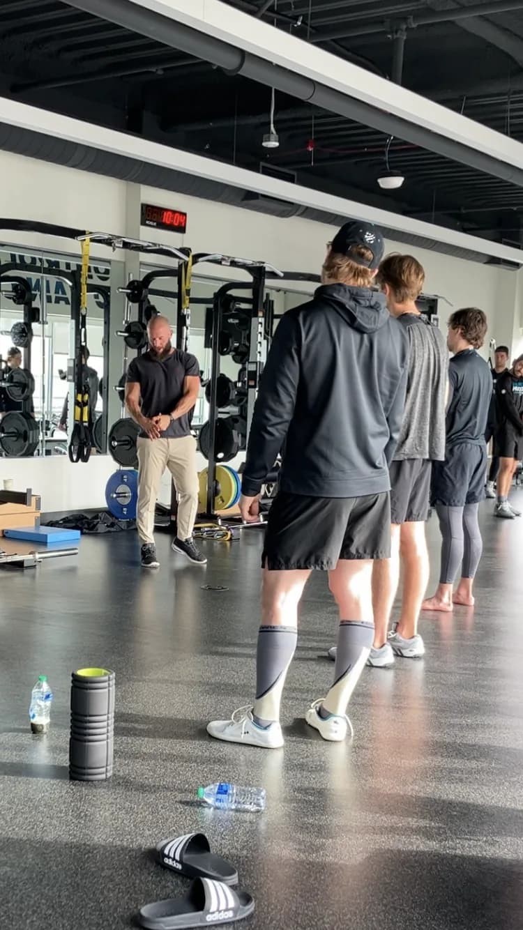 Miles coaching a group of athletes on a gym floor